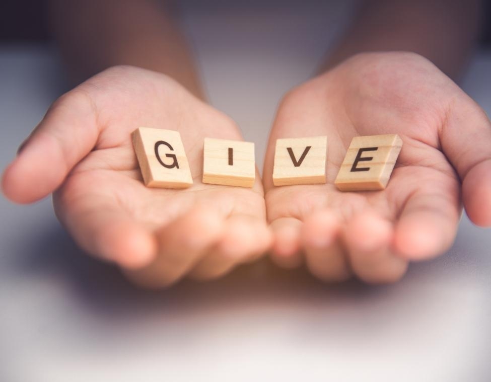 hands with give wooden letter tiles