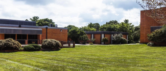 Campus Commons Area - exterior view of several brick college campus buildings surrounded by green lawns and trees.