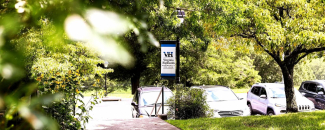Blue banner with the Virginia Highlands Community College logo hanging from a black lamppost on a tree-lined campus street