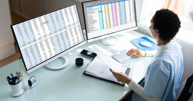 Woman seated at a desk with two computer monitors